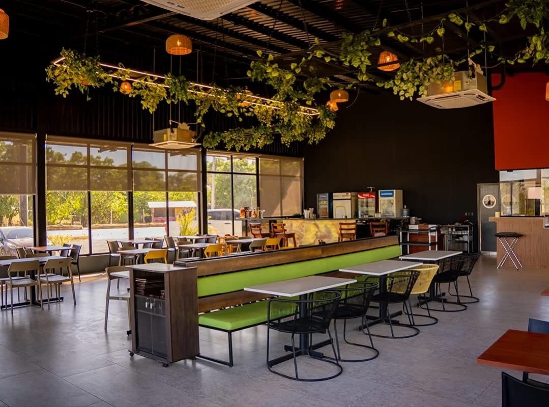 Área de mesas con vegetación colgante · Restaurante Fuego y Brazas
