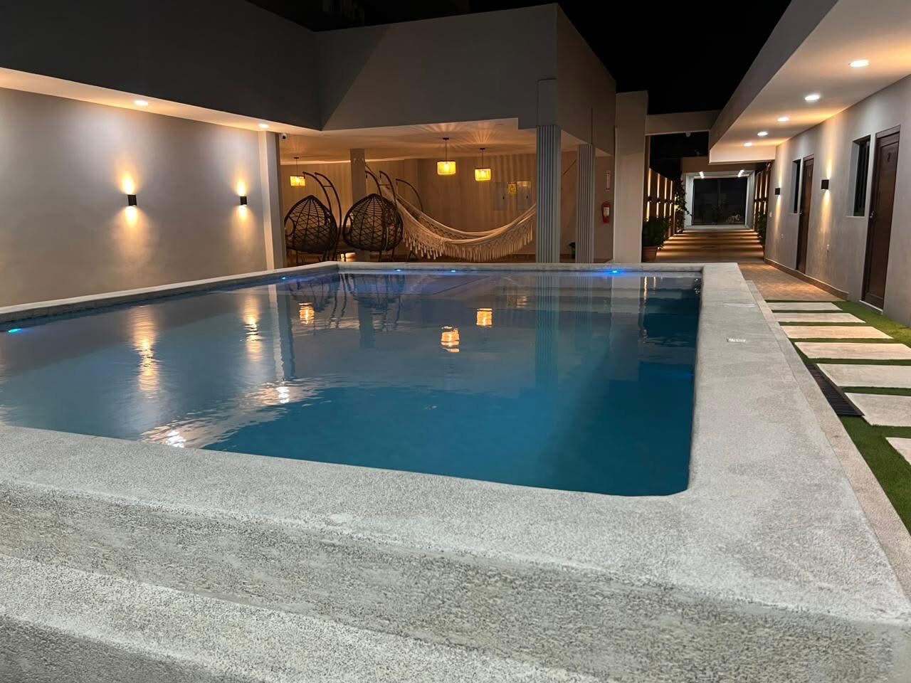 Piscina iluminada al anochecer · Hotel Silvias Inn